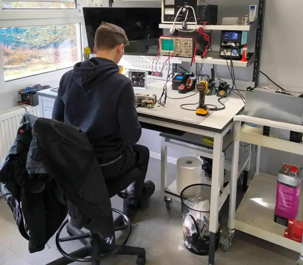 Technician repairing Okuma CNC electronic module at workbench