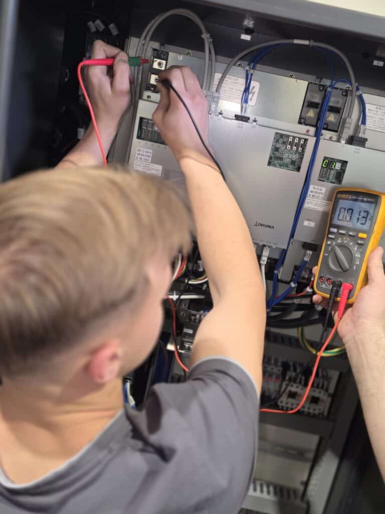 Techniker führt Diagnose und Messungen an Okuma CNC Elektronik durch